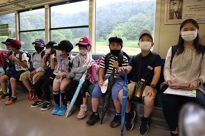 行儀よく列車のシートに座る児童たちの写真