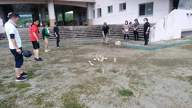 投げられたモルックの行方に注目している参加者たちの写真