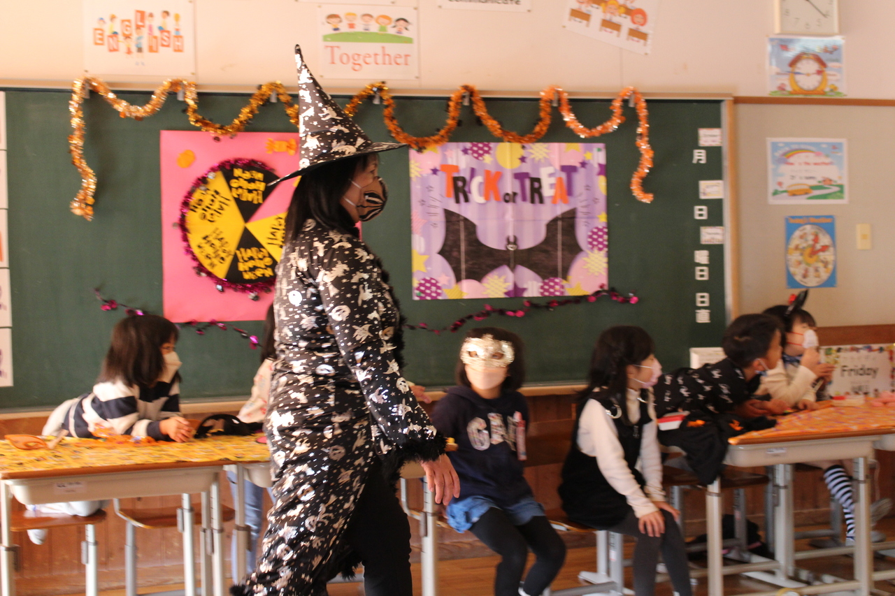 仮装をした子供たちと魔女のとんがり帽子とローブを身に纏った女性の写真