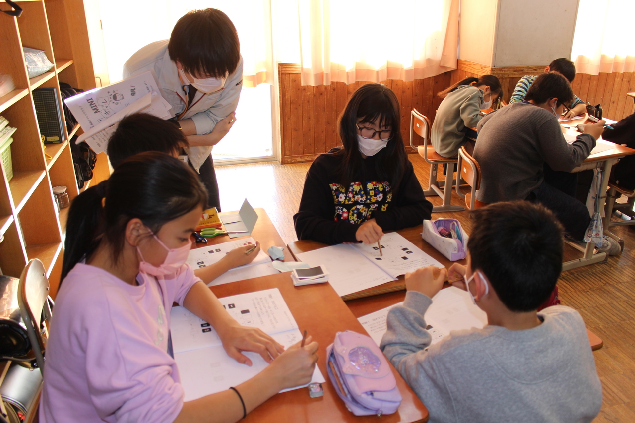 問題を解いている生徒たちを眺める大人の写真