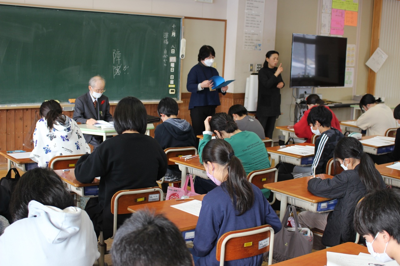 学校の教室で各々に配られた資料に目を通している児童たちの写真