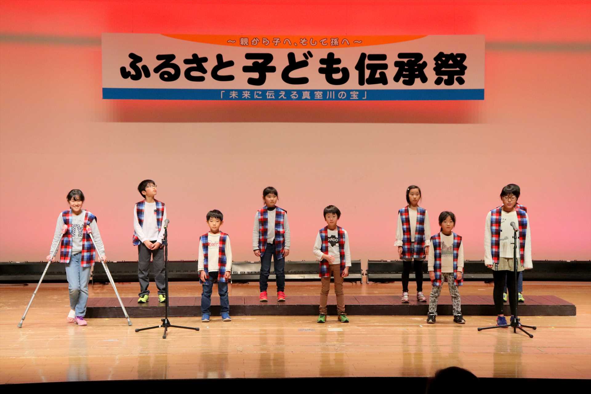 ステージ上に並ぶそろいのちゃんちゃんこを着た子供たちの写真