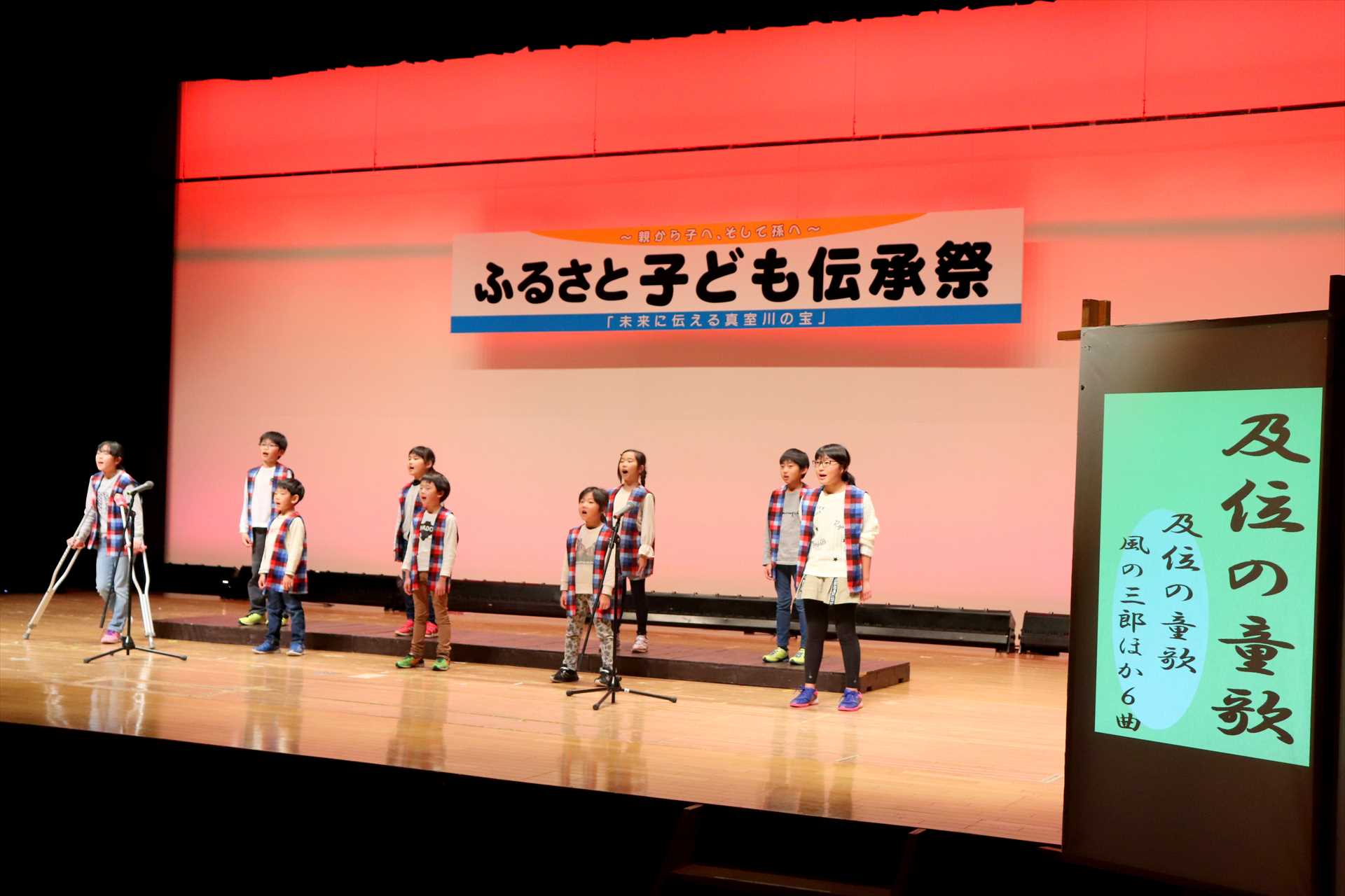 ステージの上で歌うそろいのちゃんちゃんこを着た子供たちの写真