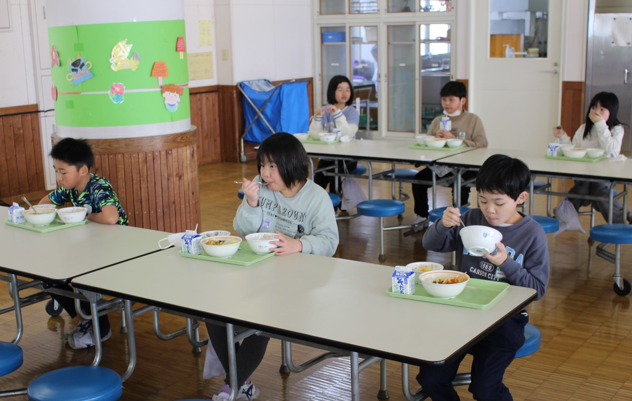 席について給食を食べる子供たちの写真