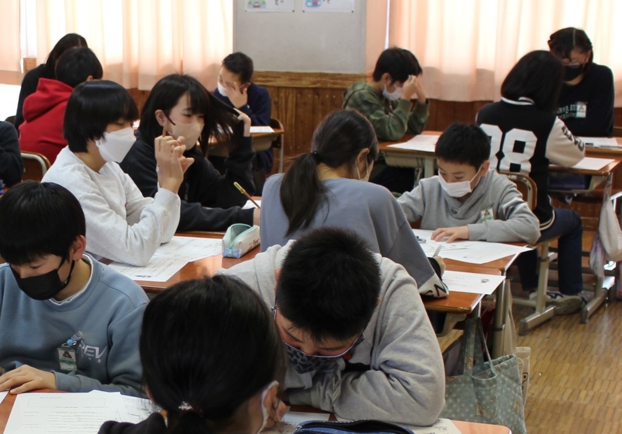 机に向かってプリントを書いている児童たちの写真