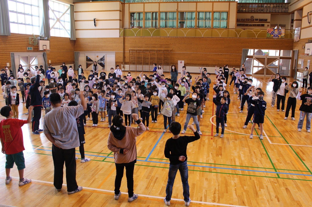 体育館で勝鬨を上げている児童たちの写真