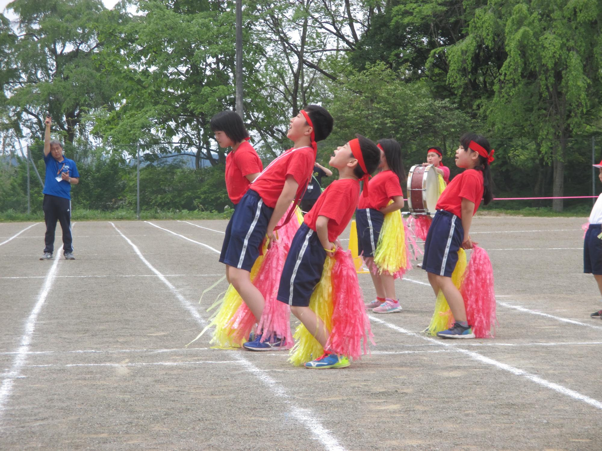 大きく胸を反らせながら大きく声を張り上げて応援する赤組児童たちの写真