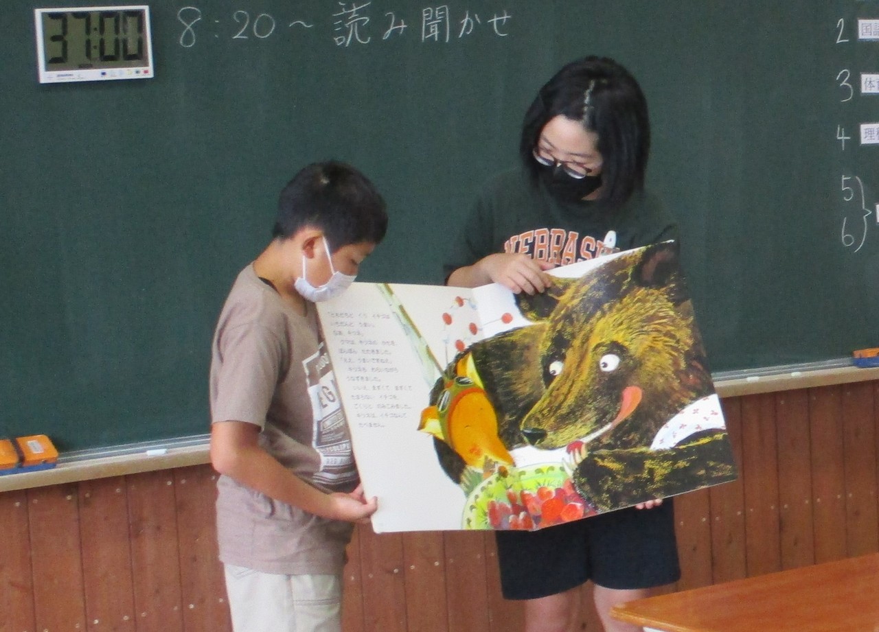 大きな熊が書かれたページの読み聞かせを行う児童2人の写真
