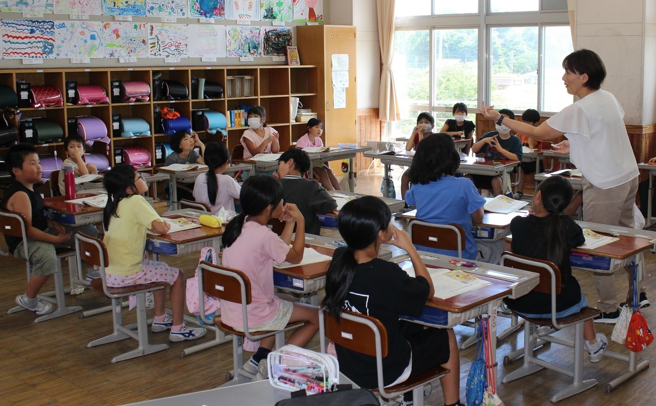 教室の中で先生の話を聞いている子供たちの写真