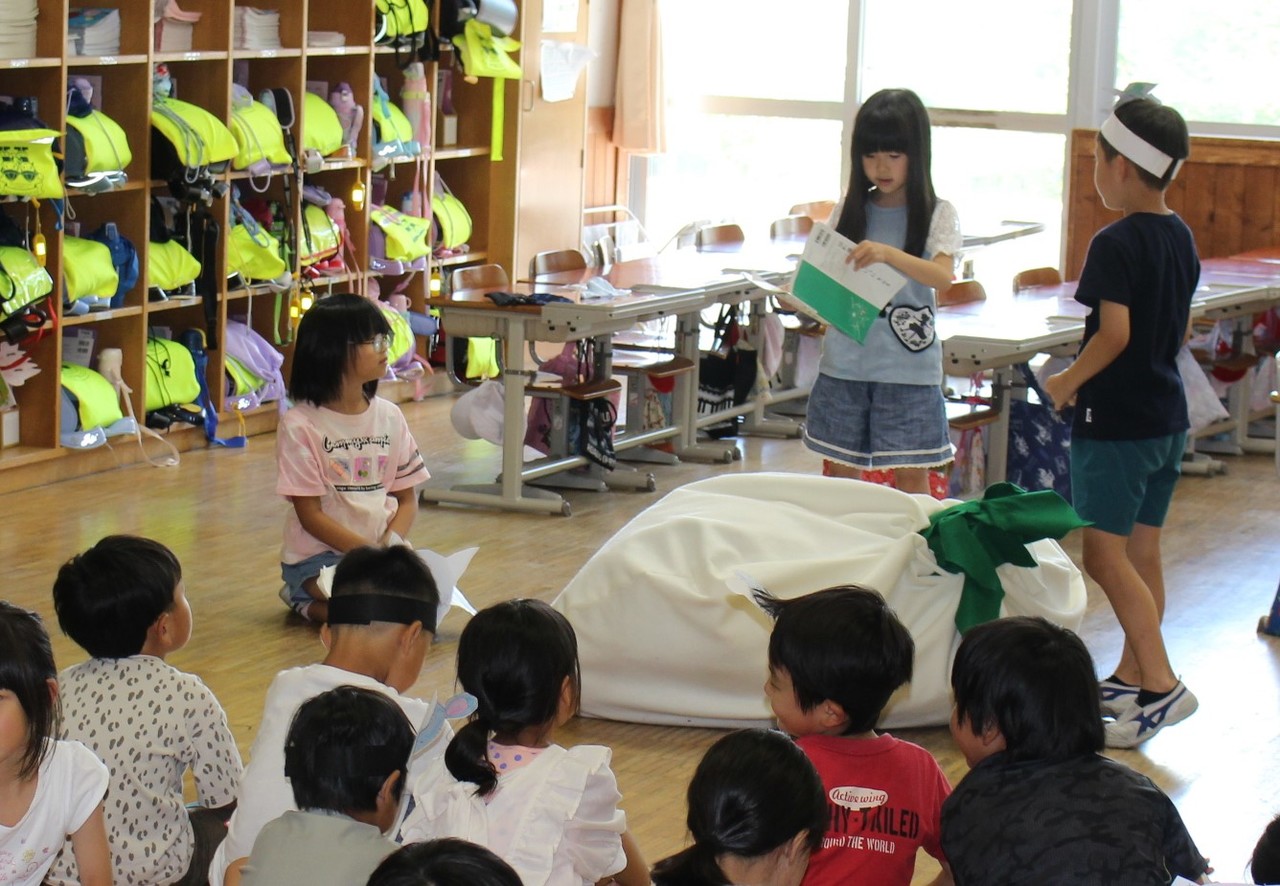 大きな布袋の前で話をする三人の子供たちの写真