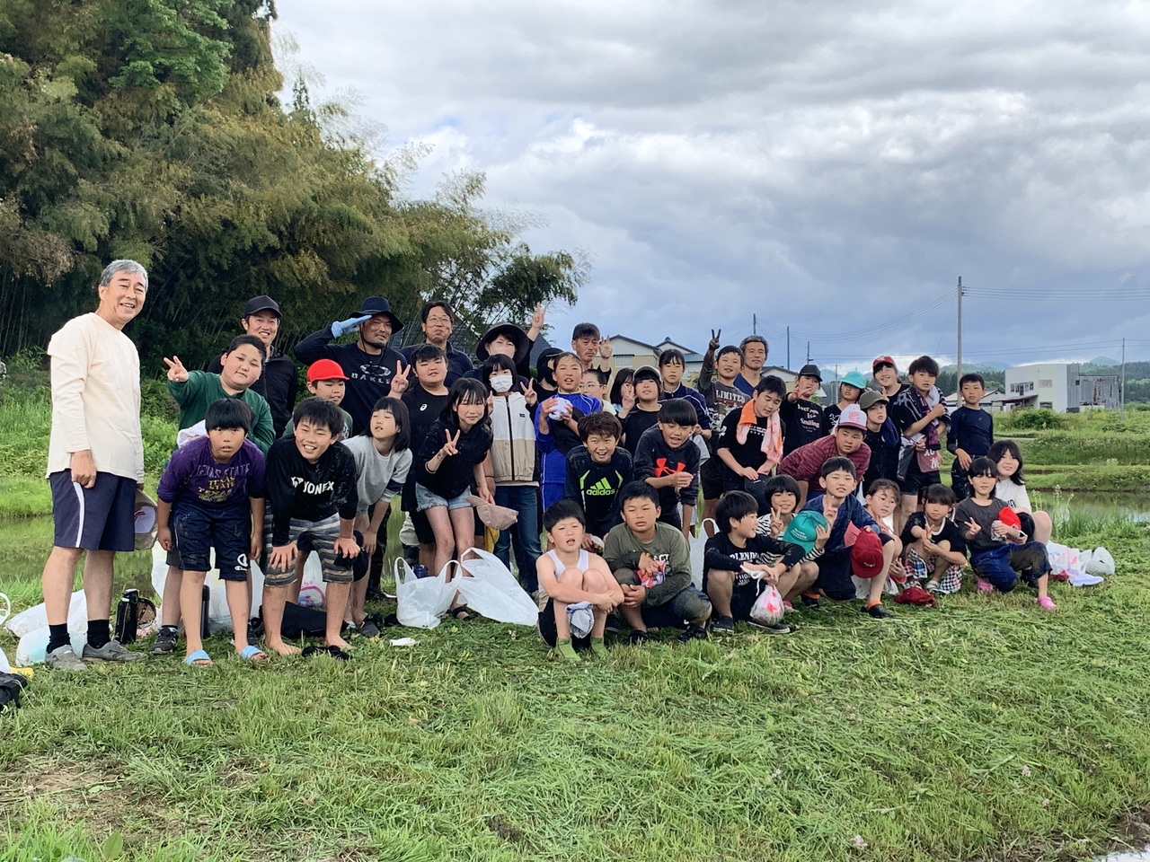 田んぼの横の土手で児童たちと男性が集合している写真