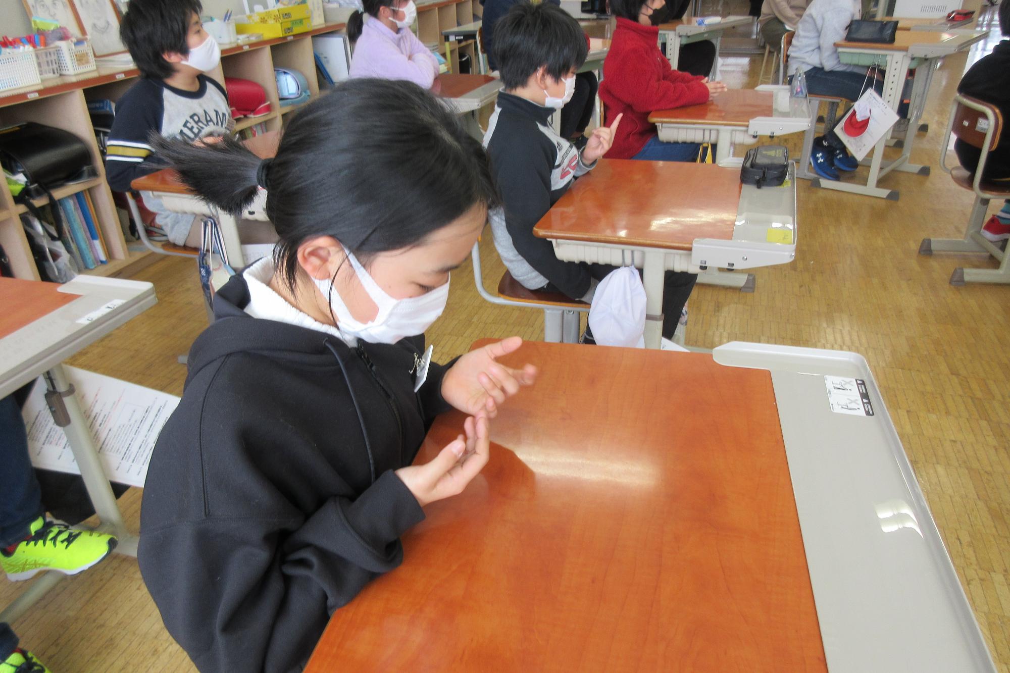 指を折って数を数えながら婦警さんの説明を理解しようとしている女の子の写真
