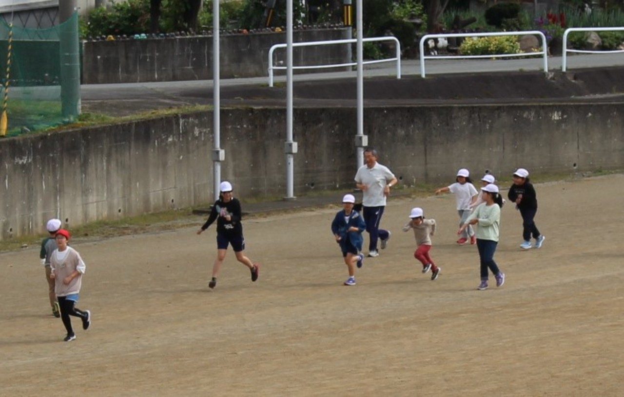 紅白帽を被った子供たちが校庭を走っている写真