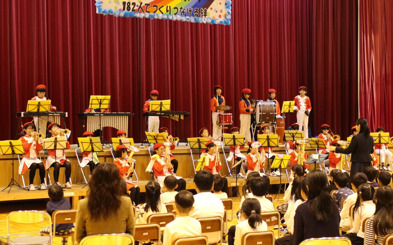 赤い衣装を着て楽器を演奏している子供たちの写真