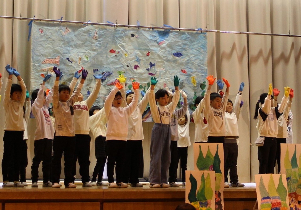 色とりどりの手袋を身に着けて手を振っている子供たちの写真