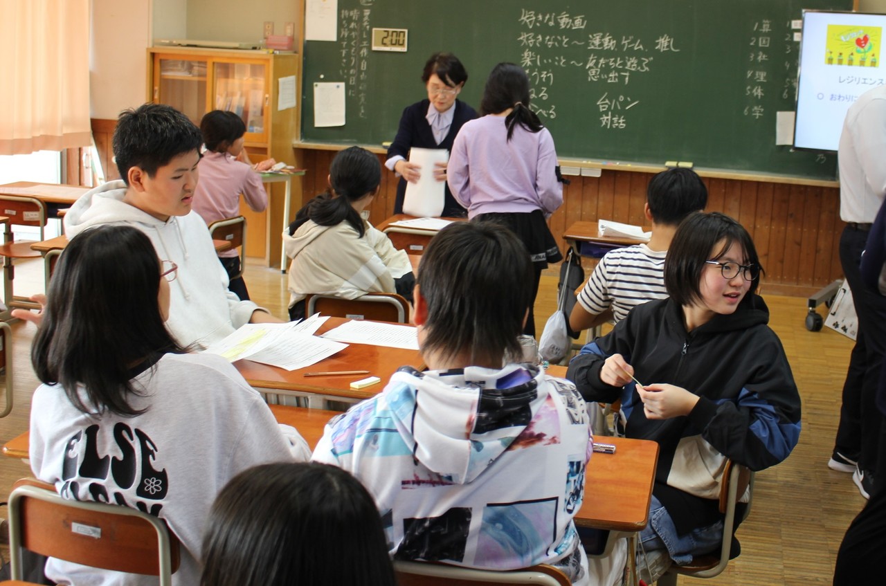 スーツ姿の女性の周りに集まる子供たちの写真