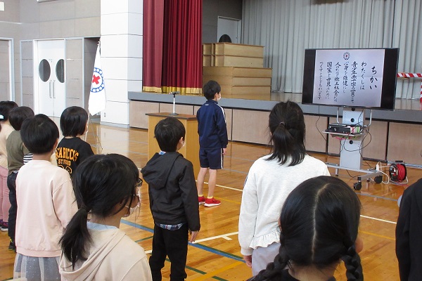 モニターに映った誓いの言葉を読み上げる子供たちの写真