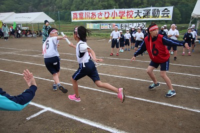 紅白で競り合いながらバトンをつなぐ瞬間の写真
