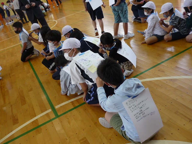 前の人の背中の画用紙に運動会の振り返りを書く生徒たちの写真