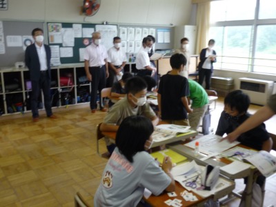 生徒たちが授業を受けている様子を見学する運営協議会メンバーの写真