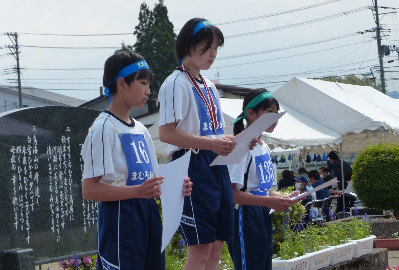 表彰台に乗った体操服姿の子供3人がそれぞれ賞状を手に持っている写真
