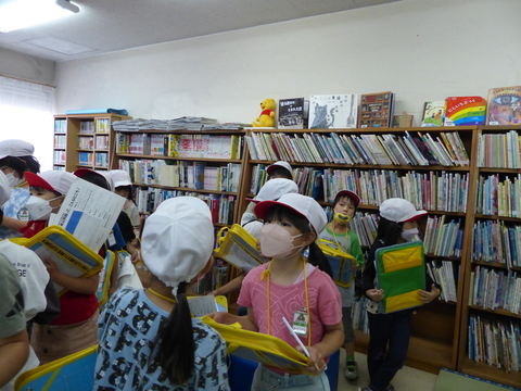 本棚の前でメモを取る児童たちの写真