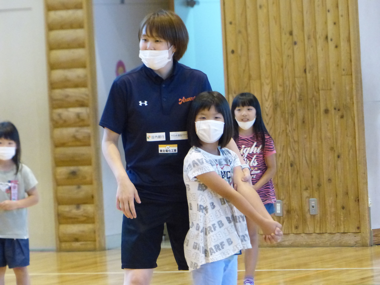 手を前に組んで構えている女の子とその子の左手を押さえているユニフォーム姿の女性の写真