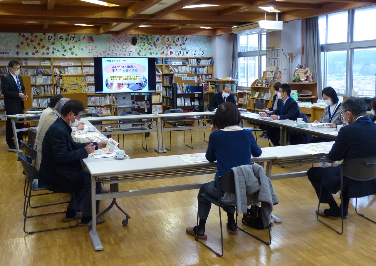口の字形に並んだ机に座り、モニターや資料を見る人たちの写真