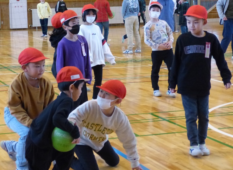体育館の中でボールを取り合って遊んでいる児童たちの写真