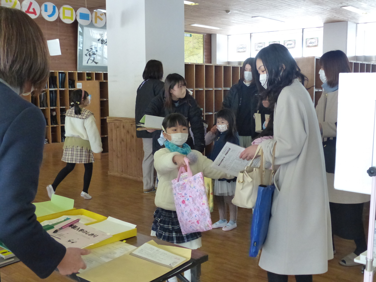 手提げバッグを持っている女の子とその横に立つ女性が資料を持った写真