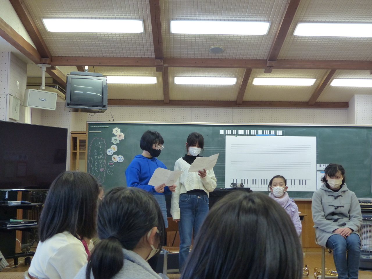 円になって座っている女子児童たちと立って話をする2人の女子児童の写真