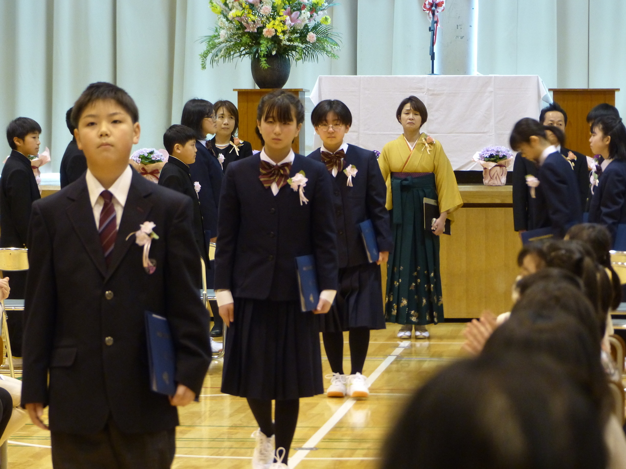 卒業証書を持って体育館を退場していく児童の写真