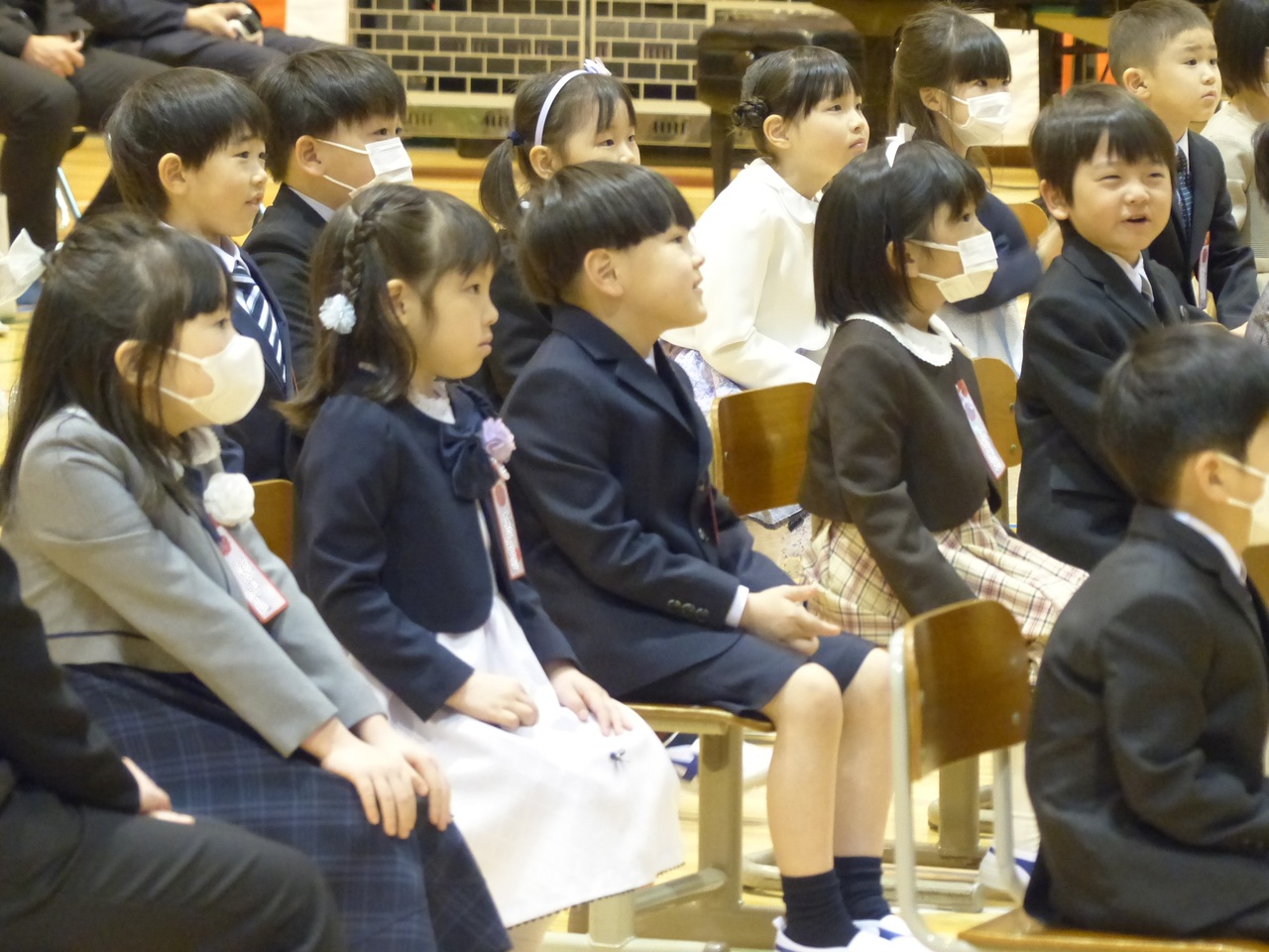 膝をそろえて椅子に座る児童たちの写真