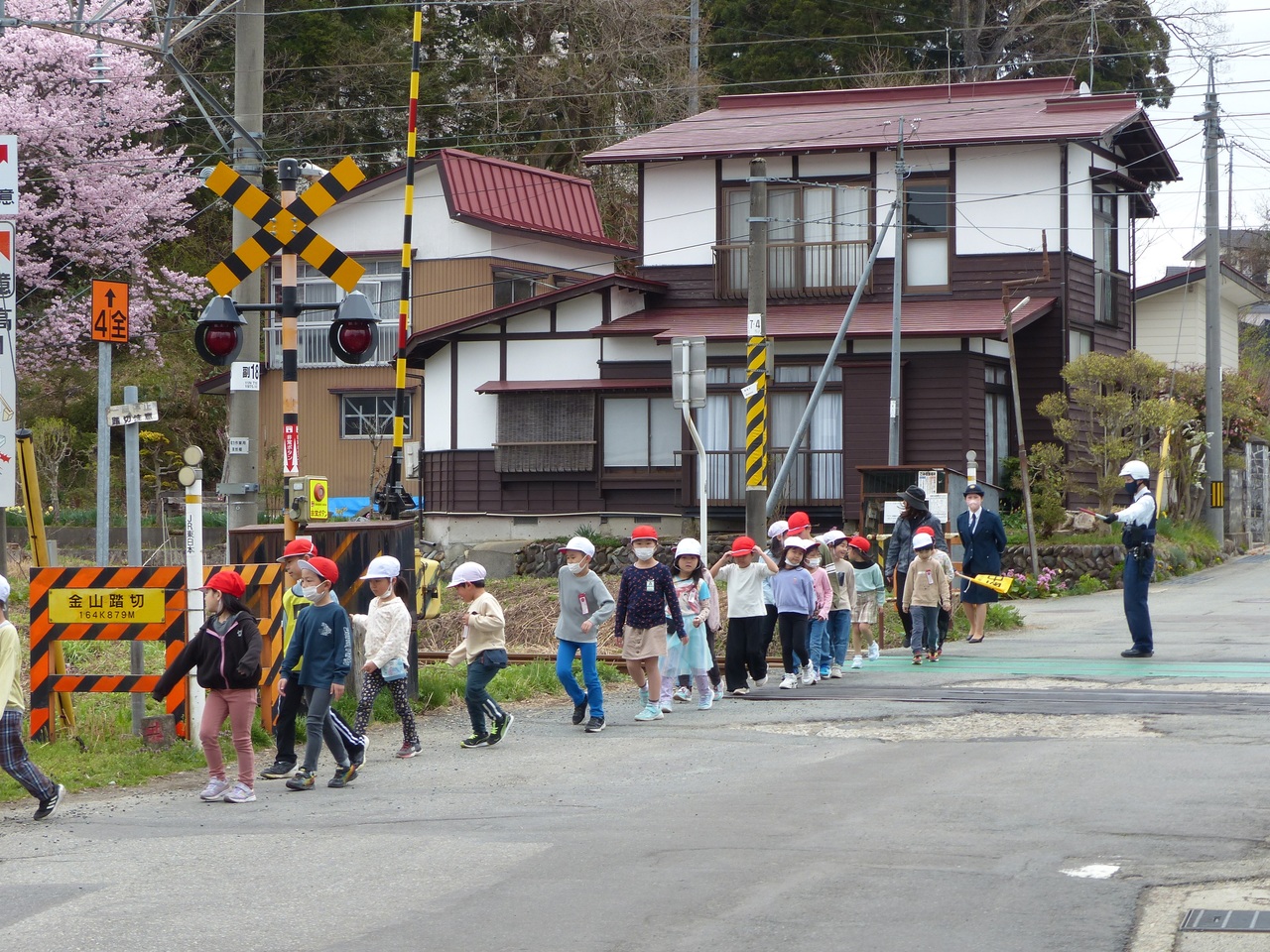 複数の児童たちが列になって踏切を渡っている写真