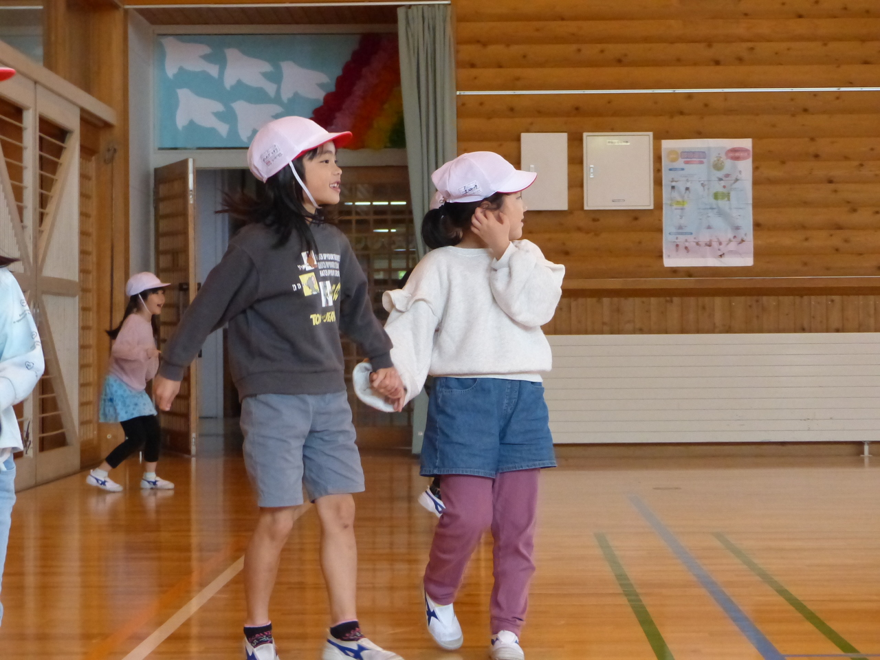 手をつないで体育館の中を歩く児童たちの写真