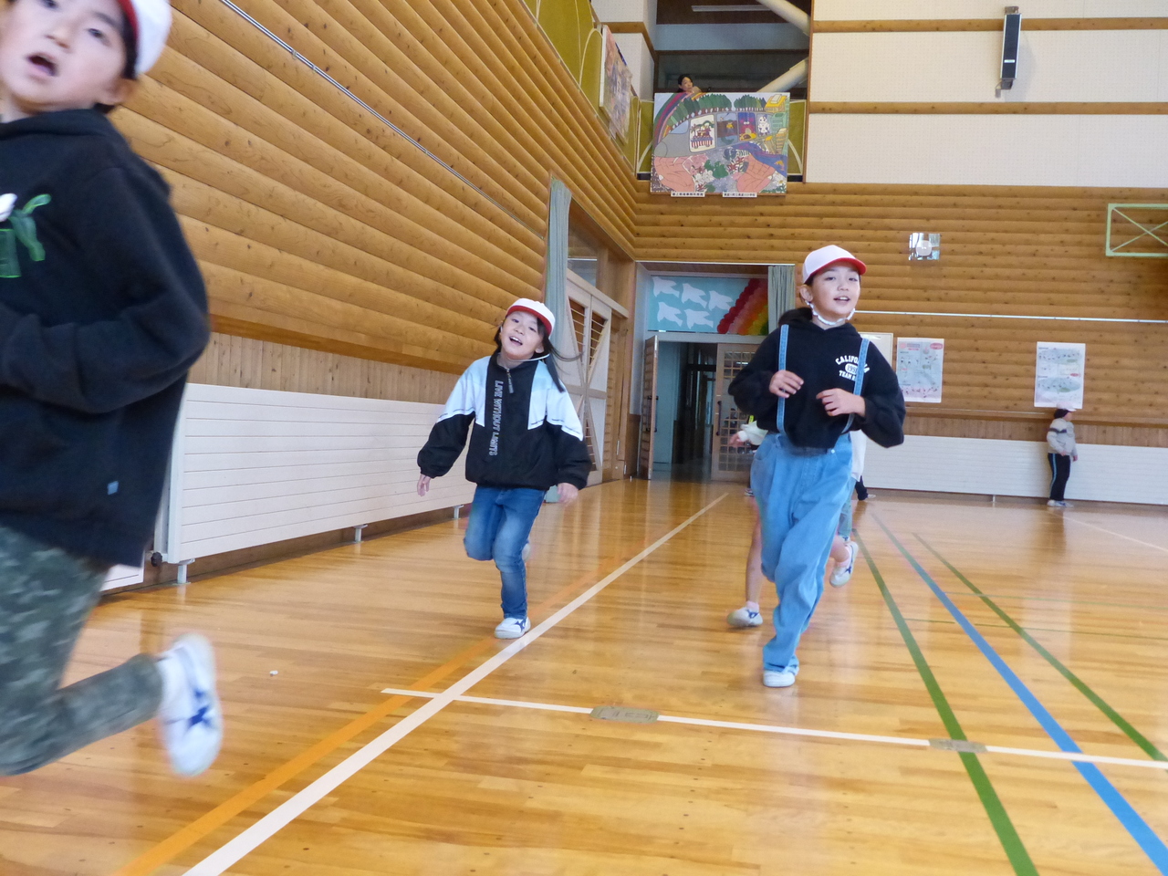 体育館の壁際で走っている子供たちの写真