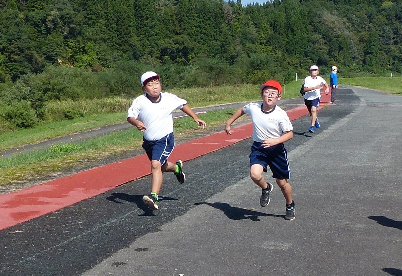 並走して道路を走る子どもたちの写真