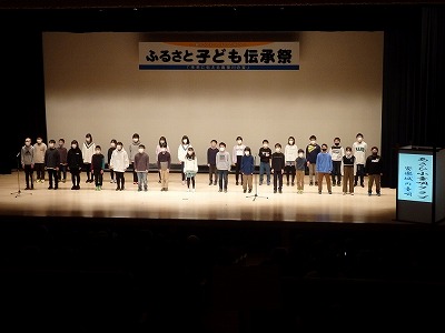 舞台上に整列した童唄クラブの児童たちの写真