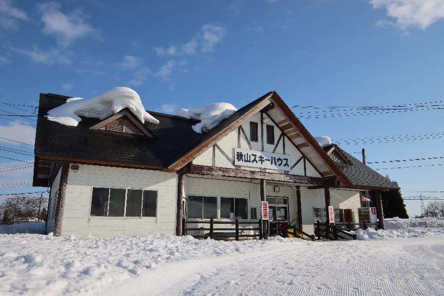 青い空を背にする雪が積もった秋山スキーハウスの写真